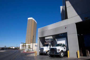 Delivery trucks unloading at a warehouse of North American supermarket highlighting the logistics & trucking industry in USA, showcasing commercial vehicles & supply chain operations in urban setting. clipart