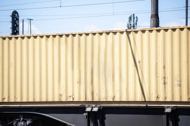 Sarı nakliye konteynırı bir trene yüklendi, çoklu modül taşımayı, kargo lojistiğini ve nakliye altyapısını gösteriyor..