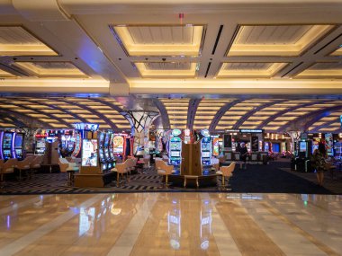 LAS VEGAS - 19 Ağustos 2024: Resorts World Las Vegas kumarhanesinde kumar makineleri, ışıklar ve dijital ekranlar. Kumarbazlar oyun makineleriyle uğraşır. Resorts World bir otel ve kumarhane kompleksi.