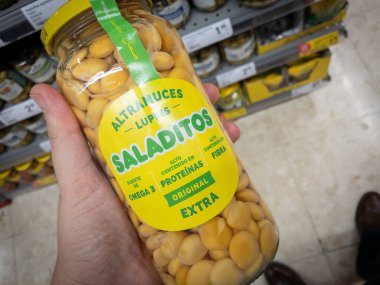VALENCIA, SPAIN - 13 Ekim 2024: Valencia 'da bir süpermarkette satışta olan ve İspanyol mutfağındaki rollerini vurgulayan bir kavanoz lupin, tatlı lupin fasulyesi, altramuces veya tremocos' un yakın plan çekimi.