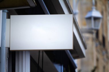 Boş bir beyaz kare tabela üzerinde seçici bulanıklık bir bina cephesinde asılı, açık bir gökyüzü ile Alman şehir caddesinde perakende ticaret reklamı için ideal.