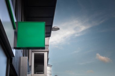 Belçika 'daki bir mağazanın önünde asılan minimalist yeşil tabela. Çağdaş bir şehir ortamında iş ilanı ya da markalaşma için modern boş bir tuval.