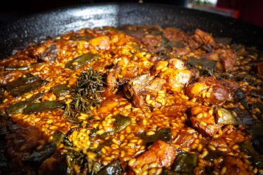 Altın ışıkla yıkanan paella valenciana, geniş ve sığ tavasında zarif bir şekilde kaynıyor. Pirinç, safran, et ve mevsimlik ürünlerden oluşan bir karışım yerel geleneklere dayanan ikonik bir İspanyol yemeği haline gelir. Bu hikaye tarifi, nesilden nesile aktarıldı.