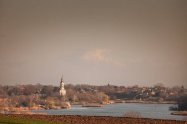 Panorama of Deliblato Serbia with Crkva Svetog Nikole, or Church of Saint Nicholas overlooking Lake Kraljevac. Deliblato is serbian village of vojvodina known for natural reserve, deliblatska pescara. clipart