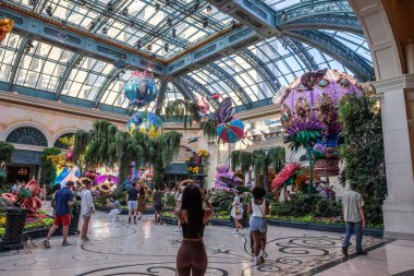 LAS VEGAS, 21 AĞUSTOS 2024: Ziyaretçiler büyük cam tavan altındaki çiçek heykellerine hayran kalarak Bellagio Konservatuvarı ve Botanik Bahçelerini keşfediyorlar. Las Vegas 'taki Bellagio Otel ve Kumarhanesi' nin bir parçası..
