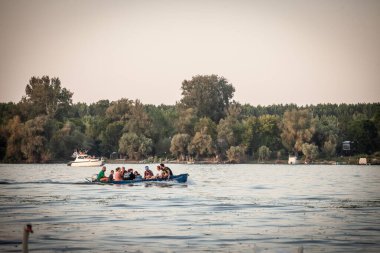 BELGRAD, SERBIA - 12 Eylül 2024: Zemun 'daki Tuna' nın sakin suları boyunca süzülen insanlarla dolu küçük bir motorlu tekne. Tuna Nehri Sırbistan 'ın ana nehri.