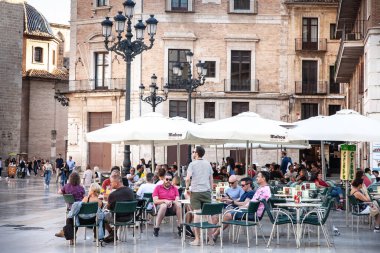 VALENCIA, İspanya - 13 Ekim 2024 Güneşli bir kare kafede, insanlar Valencia 'daki tipik bir İspanyol barında soğuk bira ve sıradan sohbetlerden hoşlanırlar..