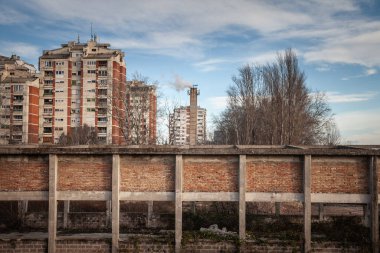 Terk edilmiş bir endüstriyel yapı, komünist dönemden kalma yüksek apartmanların önünde duruyor. Pancevo, Sırbistan 'da bu sert sahne iflası, değişen ekonomileri ve kentsel geçişi vurguluyor..