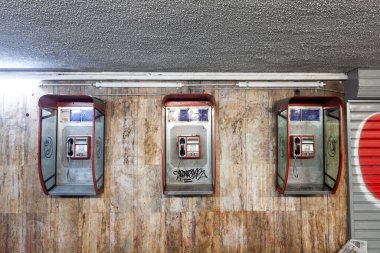 BELGRAD, SERBIA - 12 Ekim 2024: Belgrad 'da bir yeraltı geçidinde çürüyen üç ankesörlü telefon. Modası geçmiş teknoloji kentsel bozulmayı yansıtıyor, eski tasarımlar nostaljik bir şehir manzarası yaratıyor..