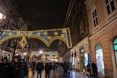 BELGRAD, SERBIA - 15 Aralık 2024: Kneza Mihailova caddesinde geceleri yürüyen seçici bulanıklık, yılbaşı ve yılbaşı süslemeleriyle aydınlatılmış, Sırbistan 'ın başkenti Belgrad' daki dükkanlar tarafından.