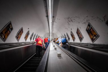 ROME, ITALY - 15 Haziran 2024: Roma metrosunun derin yürüyen merdivenlerinde, eğri bir tünel duvarındaki reklam panelleriyle çevrili. Atac tarafından işletilen Roma metrosu bir geçiş sistemidir..