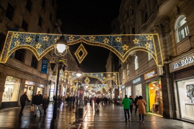 BELGRADE, SERBIA - DECEMBER 12, 2024: Selective blur on a Crowd walking at night on Kneza Mihailova street illuminated with New Year and Christmas decorations, by shops in old town in Belgrade, Serbia. clipart