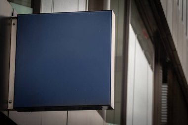 Bir Alman mağazasının önüne boş bir siyah kare tabelası asılır ve markalaşma veya reklam için minimalist alan sunulur. Gösterişli metal çerçeve modern bir ticari ortamı yansıtıyor, çağdaş perakende perakendeciler için ideal..