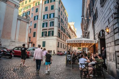 ROME, ITALY - 15 Haziran 2024: İnsanlar eski kentteki geleneksel bir pizzacı restoranının terasında yemek yemekten ve Roma tarihi sokaklarının İtalyan mutfağının ve sosyal atmosferinin özünü yakalamaktan hoşlanırlar.