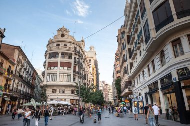 VALENCIA, İspanya - 13 Ekim 2024: Şehir merkezinde canlı bir yaya sokağı, butikler, kafeler ve tarihi cephelerle dolu. Yerel halk ve ziyaretçiler canlı dükkanlar ve mimari arasında geziniyorlar
