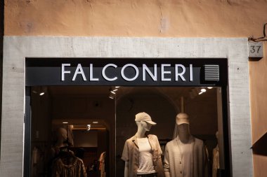 ROME, ITALY - 15 Haziran 2024: şık bir butik vitrin mankenlerinin üzerinde aydınlatılmış bir Falconeri tabelası duruyor. Falconeri, lüks kadın giyim ve erkek giyim sektöründe uzmanlaşmış İtalyan bir moda tasarımcısı..