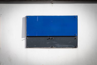 Almanya 'da bir ofis binasının dış duvarında dikdörtgen mavi bir plaket asılı. Rengi nötr arkaplan ile çelişiyor, işaret için belirgin bir boşluk sunuyor.
