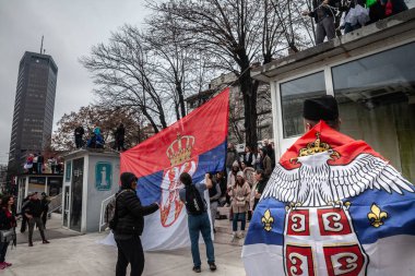 BELGRAD, SERBIA - 15 Mart 2025: Belgrad 'daki protestocular,' Krvave su vam ruke 'veya 15 Mart' ta Vuciç rejimine karşı düzenlenen protestolar sırasında Sırp bayraklarını göndere çekiyorlar.