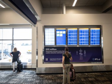MINNEAPOLIS - 23 AUGust 2024: Minneapolis-Saint Paul Havalimanı 'ndaki (MSP) bilgi ekranlarında uçuş kontrolleri yapan yolcular, seyahat planlama, havaalanı yolcu faaliyetlerini gösteren.