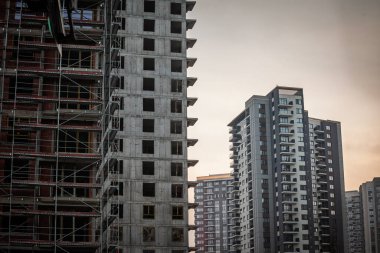 İnşaat alanı, beton yapıları, iskelesi ve kentsel emlak gelişimini temsil eden modern apartmanları olan yüksek binaları gösteriyor..