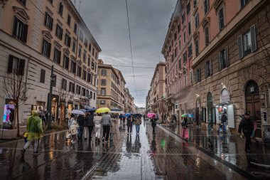 ROMA, İtalya - 15 Ocak 2025: Roma 'da yağmurlu havalarda Roma' da işlek bir alışveriş caddesi olan Via Ottaviano boyunca yürüyen şemsiyeli insanlar, Roma 'nın canlı şehir yaşamını ve şehir atmosferini yakalıyorlar