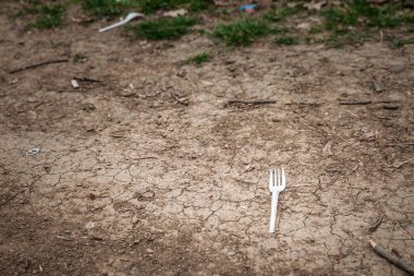Çatlak toprağa çöp ve çöp olarak atılan tek kullanımlık plastik çatal plastik çatal plastik çatal, çatal bıçaklar ve çatal bıçaklar gibi tek kullanımlık plastik kirliliğin yol açtığı çevresel hasarı gösteriyor..