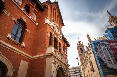 VALENCIA, SPAIN - 13 Ekim 2024: Valencia 'daki Concejalia de Comercio y Abastecimiento cephesinde Iglesia de los Santos Juanes kilisesi arka planda, belediye yönetimini sembolize etmektedir..