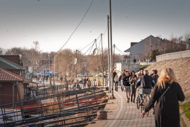 PANCEVO, SERBIA - 3 Mart 2025: Sırbistan 'ın Pancevo kentindeki Tamiski Kej' de boş vakitlerin tadını çıkaran kalabalık, toplumsal atmosferi ve kentsel sosyal hayatı yansıtıyor.