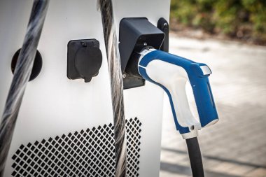 Kamu şarj istasyonundaki elektrikli araç şarj cihazına seçici bir şekilde odaklanarak, çevre dostu hareketlilik ve sürdürülebilir ulaşım çözümleri ve EV elektrikli arabaların geliştirilmesini vurguluyor.
