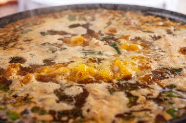 Valensiyalı otantik paella (paella valenciana) in valencia, spain, pişirme kabaran çorba ile büyük bir tavada, zengin renkler ve geleneksel hazırlama metodu gösterilir