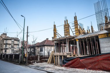 Sırbistan 'daki inşaat sahasında, beton yapılar ve yapı iskeleleri olan bir kentsel alanda devam eden iskan gelişimi resmediliyor.