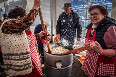 Back PETROVAC, SERBIA - FEBRUARY 15, 2025: Backi Petrovac 'taki bir pazarda cvarci pişiren kadınlar. Cvarci ya da cvarak, tipik bir Sırp yemeği olan yağlı domuz derisi..