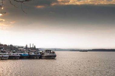 Tuna 'daki Smederevo sırtına demirlemiş bir nehir mavnası ve itme botu hattı uzanır, akşam sisi uzak tepeleri yumuşatırken alçak kış güneşi Avrupa' nın dalgalı sularının en yoğun sularında parlarken