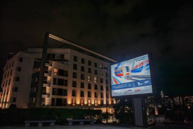 BELGRAD, SERBIA - 21 Mart 2025: Parlak ışıklandırılmış Rus Demiryolları afişlerinin Geleceği İçin Birlikte Bina 'yı ilan eden, Sırbistan ve Balkanlar' daki Rus etkisini gösteren gece görüşü.