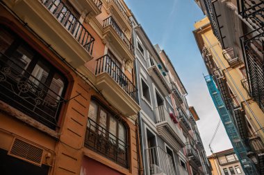 Renkli, balkonlu apartman blokları Valencia 'nın tarihi merkezinde dar bir şerit oluşturdu. Pürüzlü korkuluklar, pastel sıva ve İspanya' da bir emlak sembolü olan mavi gökyüzü.