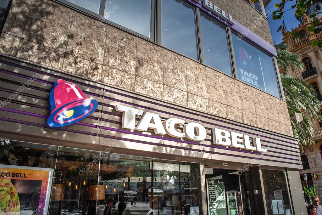 VALENCIA, SPAIN - OCTOBER 13, 2024: Bold bell logo lettering announces Taco Bell fastfood outlet off Valencia Plaza Ayuntamiento, illustrating the US TexMex chains expansion across Spain and Europe