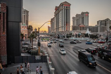 LAS VEGAS, 21 AĞUSTOS 2024: Las Vegas Bulvarı 'nda ışıklar yanıp sönerken Sezar Sarayı' ndan geçen alacakaranlık trafiği Pastel çöl gökyüzüne karşı şeritlerin sürekli hareketini yakalıyor.