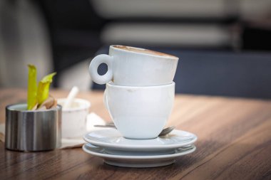İki boş espresso fincanı, kahve fincanı, kaşık kaşık dolu çay tabakları üzerinde istiflenmiş kahve sonrası molasını gösteriyor..