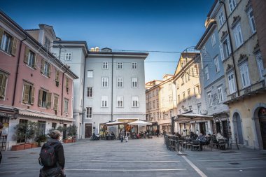 TRIESTE, ITALY - 17 Aralık 2024: Trieste İtalya 'nın Citta Vecchia' sı boyunca, cephelerin, pencerelerin ve kafe teraslarının kışın yayaları çerçevelediği küçük bir meydan.