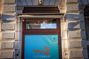 TRIESTE, ITALY - 17 Aralık 2024: Düşük güneş ışığı, İtalya 'nın Trieste kentindeki bir taştan perinin üzerinde İtalyan telekom enerji markasının sinyalini veren bir WindTre 