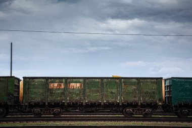Paslanmış yeşil teleferik vagonları Letonya, Jelgava 'da bir tren istasyonunda duruyor. Batı yaptırımlarına rağmen kömür ihracatı için Rus Demiryolları tarafından işletilen yük vagonları bulutlu gökyüzünün altında boşta duruyor..