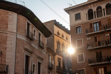 Valencia 'daki ciutat Vella daireleri, tuğla cepheleri, işlenmiş demir balkonlar ve İspanya' daki gayrimenkullerin sembolü olan çeşitli tarihi çatılar arasında sıcak gün batımı ışıkları parlıyor..