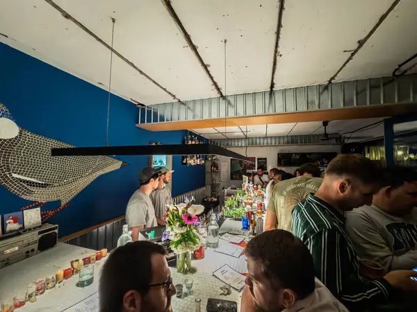 BELGRAD, SERBIA - 15 Mart 2025: Müşteriler, yoğun bir akşamda modern aydınlatma altında içki sipariş ederek Sırbistan 'ın orta kesimindeki modaya uygun bir gece barının tezgahını doldurdular.