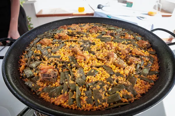 Bitmiş paella valenciana (valencian paella) geniş bir tavada dinlenir; tavşanlı, tavuklu ve yeşil fasulyeli altın pirinç Valencia toplumunda güneşli bir terasta servis edilmeye hazırdır.