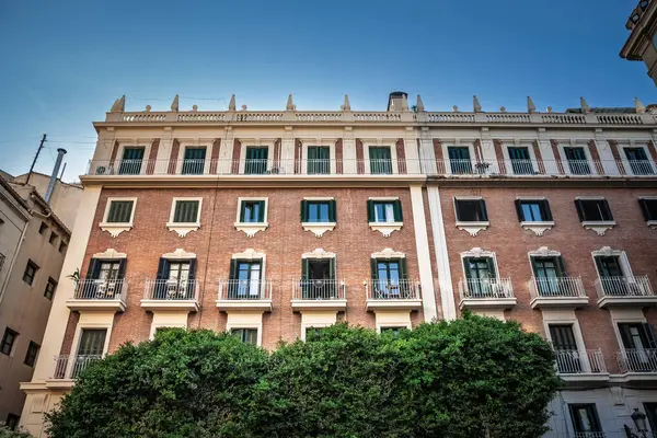 Ciutat Vella 'daki tuğla ve sıva dairede yeşil kepenkli pencereler, demir balkonlar, yoğun çalılıkların üzerindeki neo-klasik korna, şehir merkezindeki emlak mirasını gösteriyor