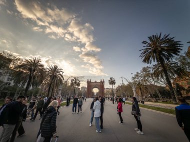BARCELONA, SPAIN - 12 Nisan 2025: Akşam kalabalığı, Passeig de Lluis Şirketi boyunca Barselona 'da Arc de Triomf tarafından gün batımında ele geçirildi. Bu bir kapı ve katalonya 'nın simgesi..