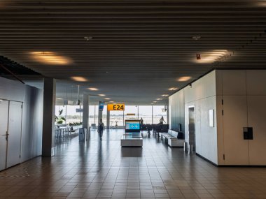 AMSTERDAM, NETHERLANDS - 21 AĞUSTOS 2024: Amsterdam Schiphol Gate E24 'ün sessiz iç mekanı, içi boş fayanslı oturma odaları, banklar, bilgi ekranları ve Avrupa havaalanı tasarım pencereleri,.