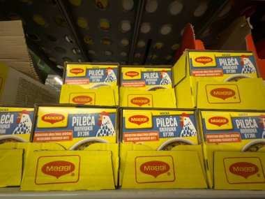 BELGRAD, SERBIA - 15 Mart 2025: Belgrad 'da bir süpermarket rafında karton tepsilerde istiflenmiş sarı Maggi tavuk suyu küpleri. Maggi, Nestle 'ın bir parçası olan İsviçre sosu ve baharatların bir markasıdır..