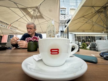 BELGRAD, SERBIA - 15 Mart 2025: Şemsiyelerin altındaki bir kafe masasında bir espresso bardağının üzerinde Saicaf logosu. Zanetti 'nin bir parçası olan Saicaf, İtalyan kahve kızartma makinesi ve yapımcısıdır..