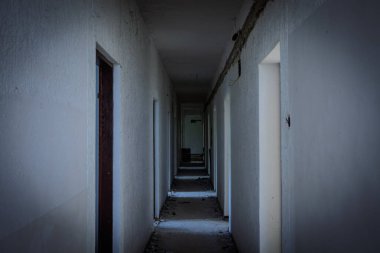 Terk edilmiş otel koridoru enkaz ve kayıp eşyalar ile dolu; kapı çerçeveleri karanlığa çekiliyor, kentsel çürümeyi iletiyor, ürkütücü atmosfer ve keşif fotoğrafçılığının cazibesi.